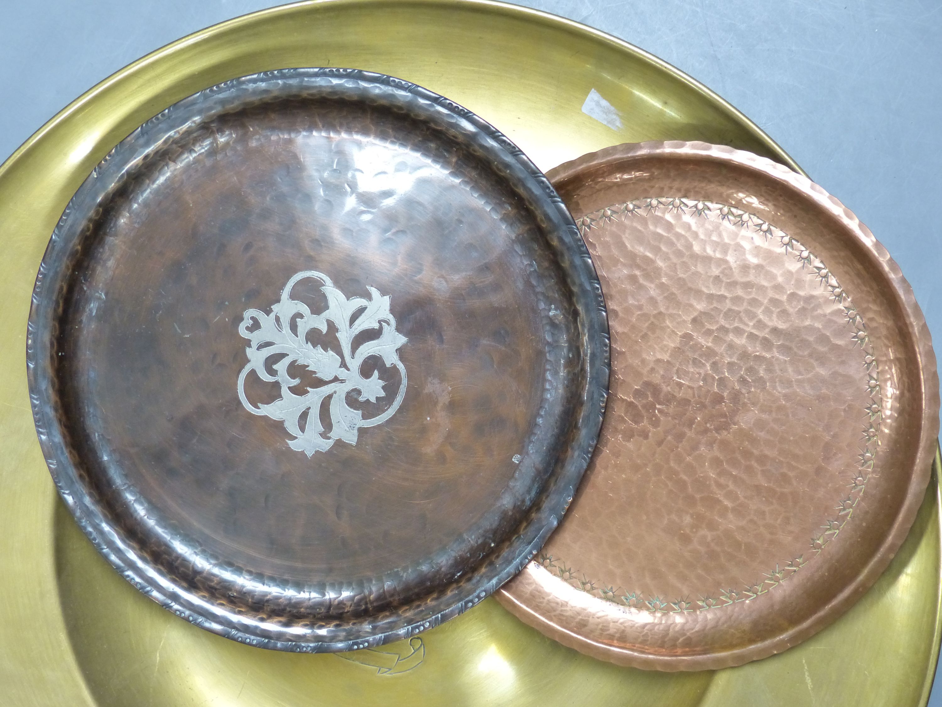 A Hugh Wallace hammered copper dish, a Taunton brass alms dish and another hammered copper dish, diameter 46cm